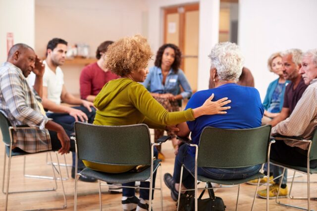 caregiver-support-group-meeting Caregiver support group sitting in a circle offering comfort